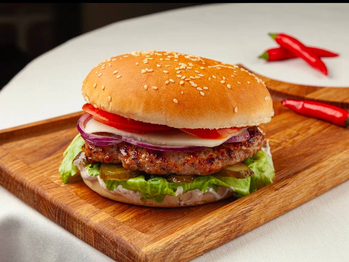 Original restaurant burger photo on a wooden board with a pale table background