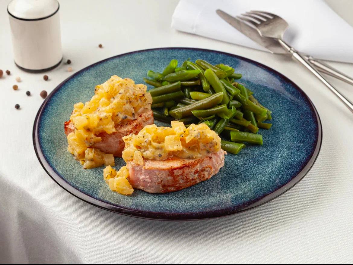 Original restaurant food photo with pork medallions, yellow sauce, and green beans on a blue plate